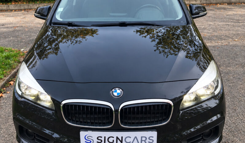 BMW noir devant une haie verdoyante